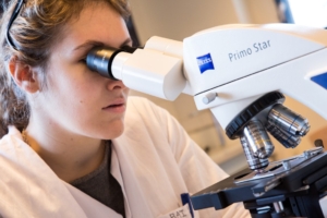 technicienne qui analyse au microscope des bactéries